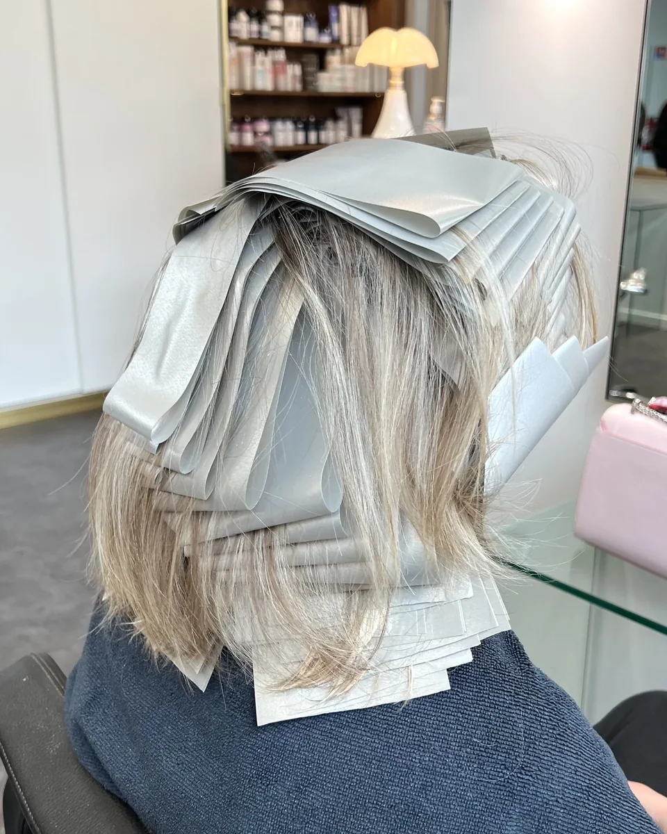 Babylights en cours au salon : de nombreuses mèches fines sont séparées dans des papillotes.