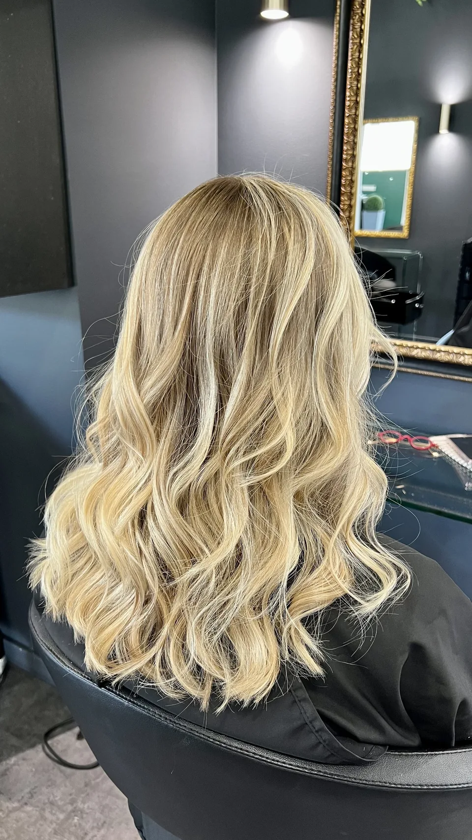 Résultat du balayage californien vu de dos : longueurs blondes lumineuses et ondulations.